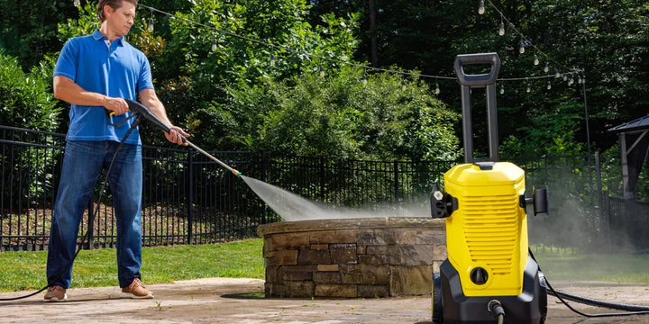 Karcher pressure washer cleaning a stone patio in a backyard